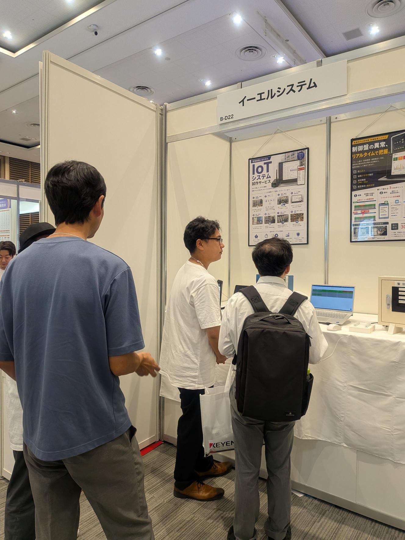 EdgeTech+ West 2026の当社ブースで、説明員が来場者に説明している様子